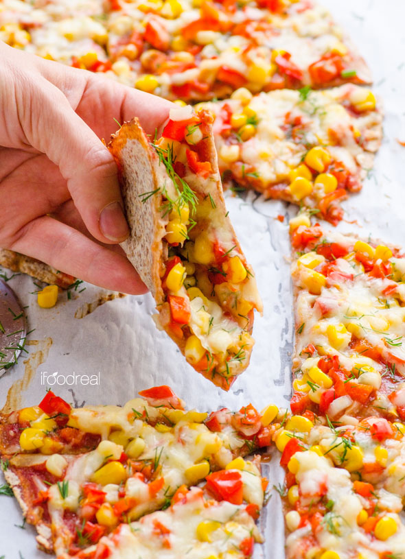 holding-sprouted-grain-tortilla-pizza-corn-pepper-garlic-sauce