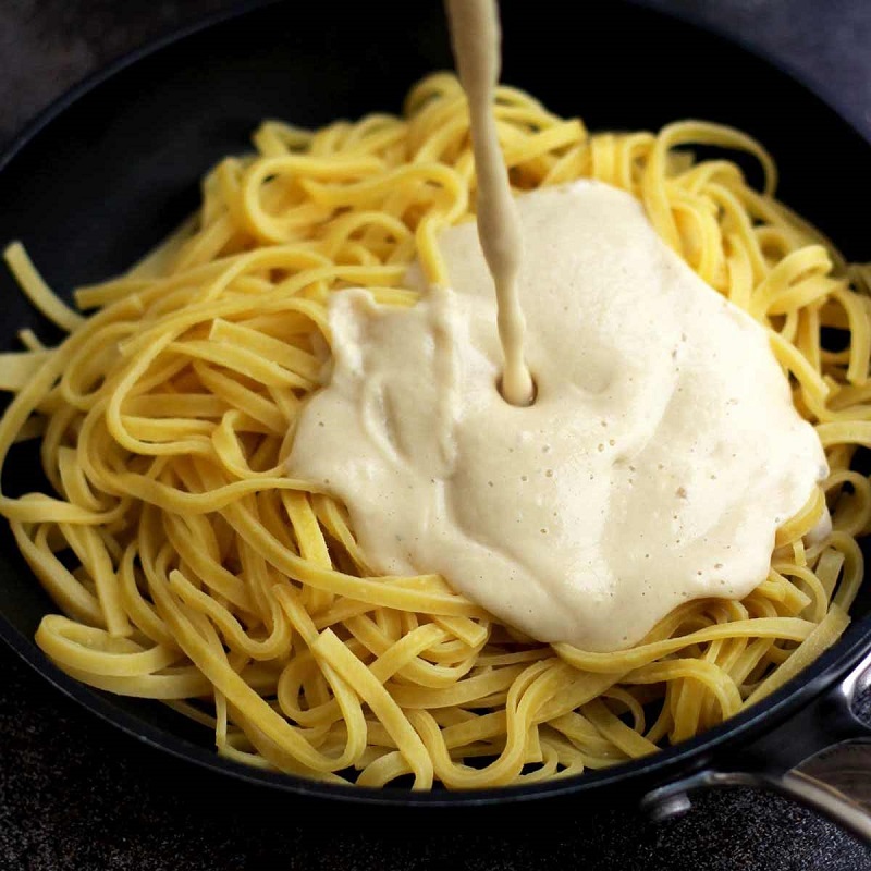 Vegan-Fettuccine-Alfredo-Sauce-Being-Poured-Over-Pasta-square